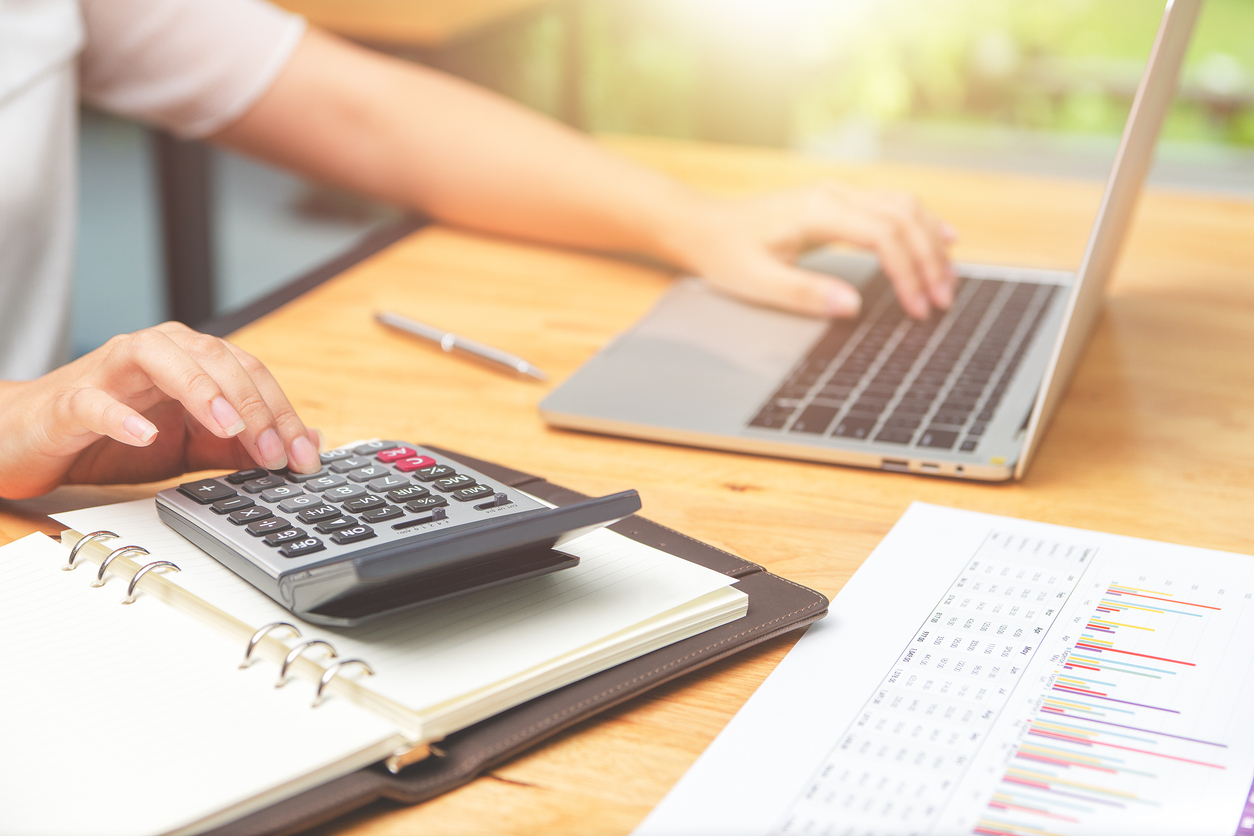 Treballador utilitzant ordinador amb papers i calculadora