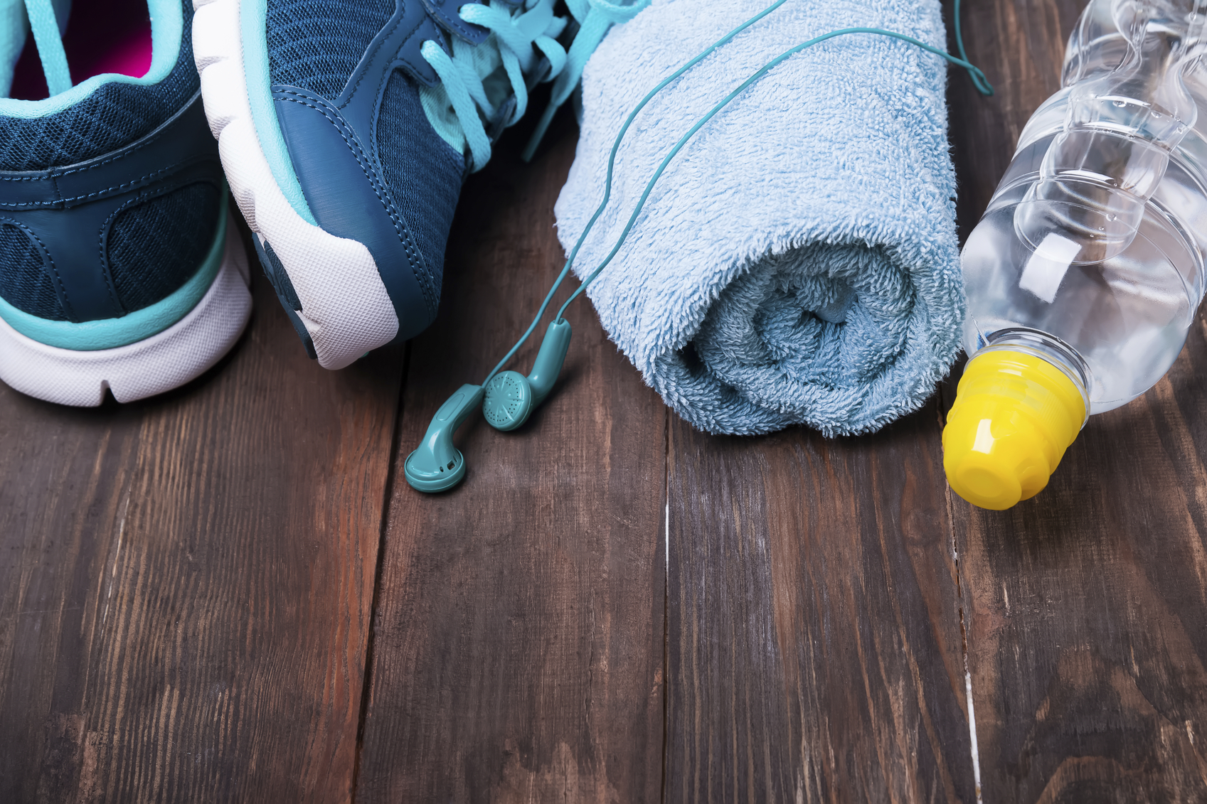 Primer plano de zapatillas de deporte, auriculares, toalla y botella agua
