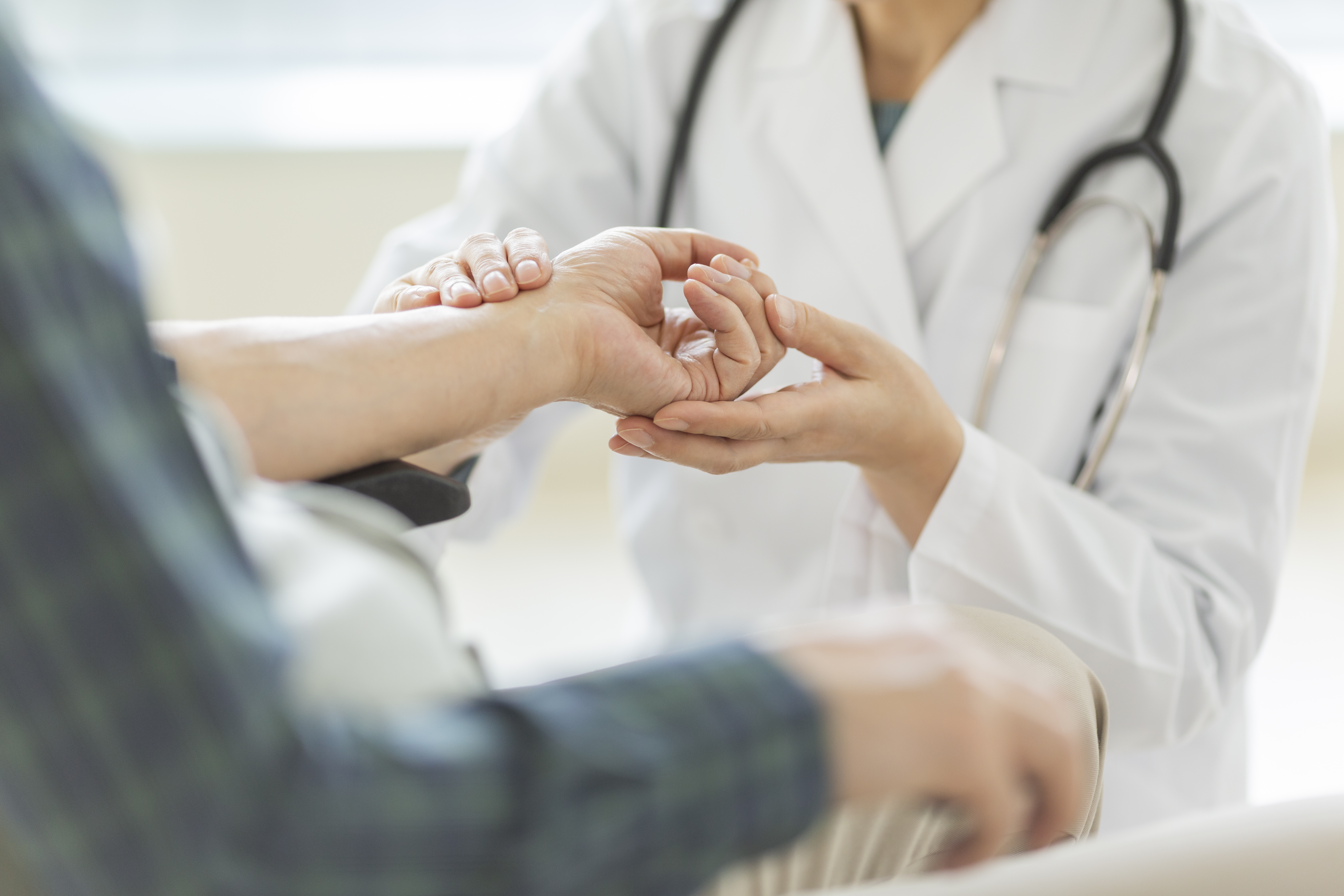 Una professional sanitària agafa la mà d'un pacient. 