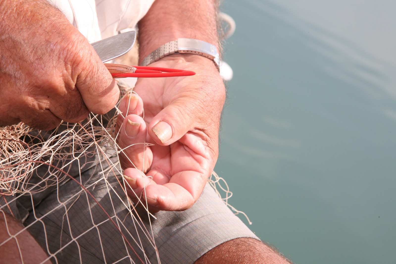 Unes mans arreglen una xarxa de pescar