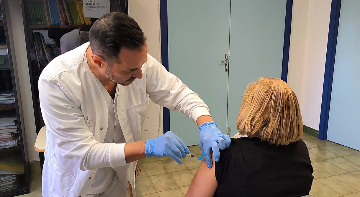 Un professional sanitari posa una vacuna a una dona.