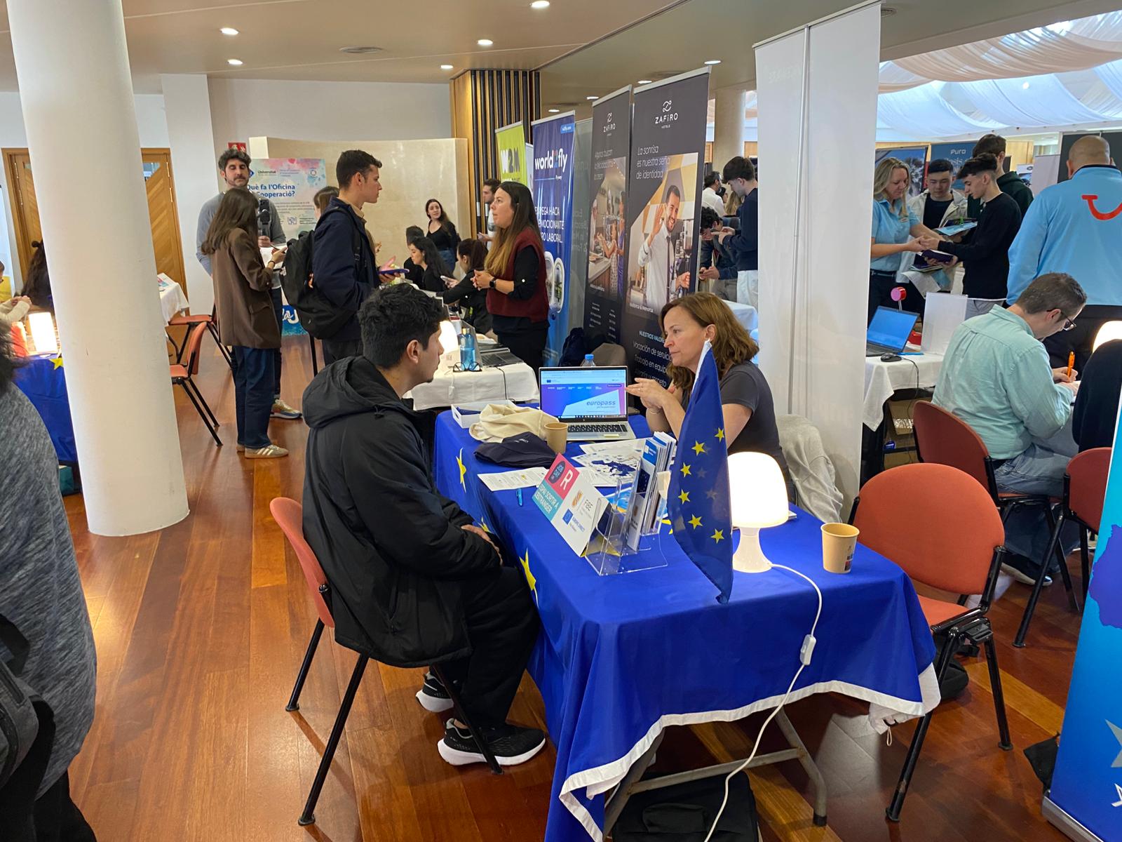 Estand del Govern al Job Day UIB, on una treballadora manté una conversa amb un jove.