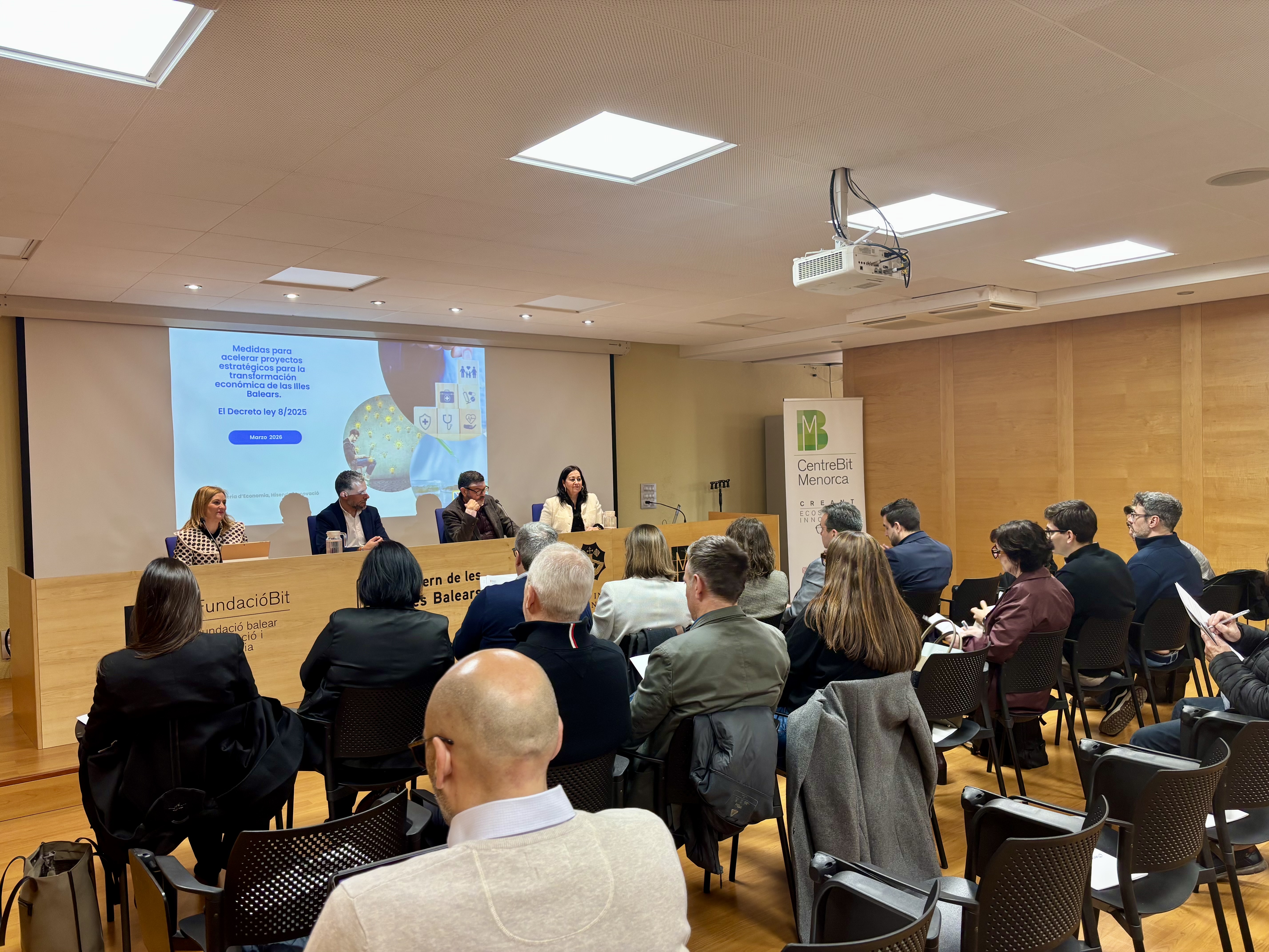 Els ponents de la jornada de presentació de la Unitat Acceleradora de Projectes Estratègics (UAPE) asseguts davant del públic en un saló d'actes.