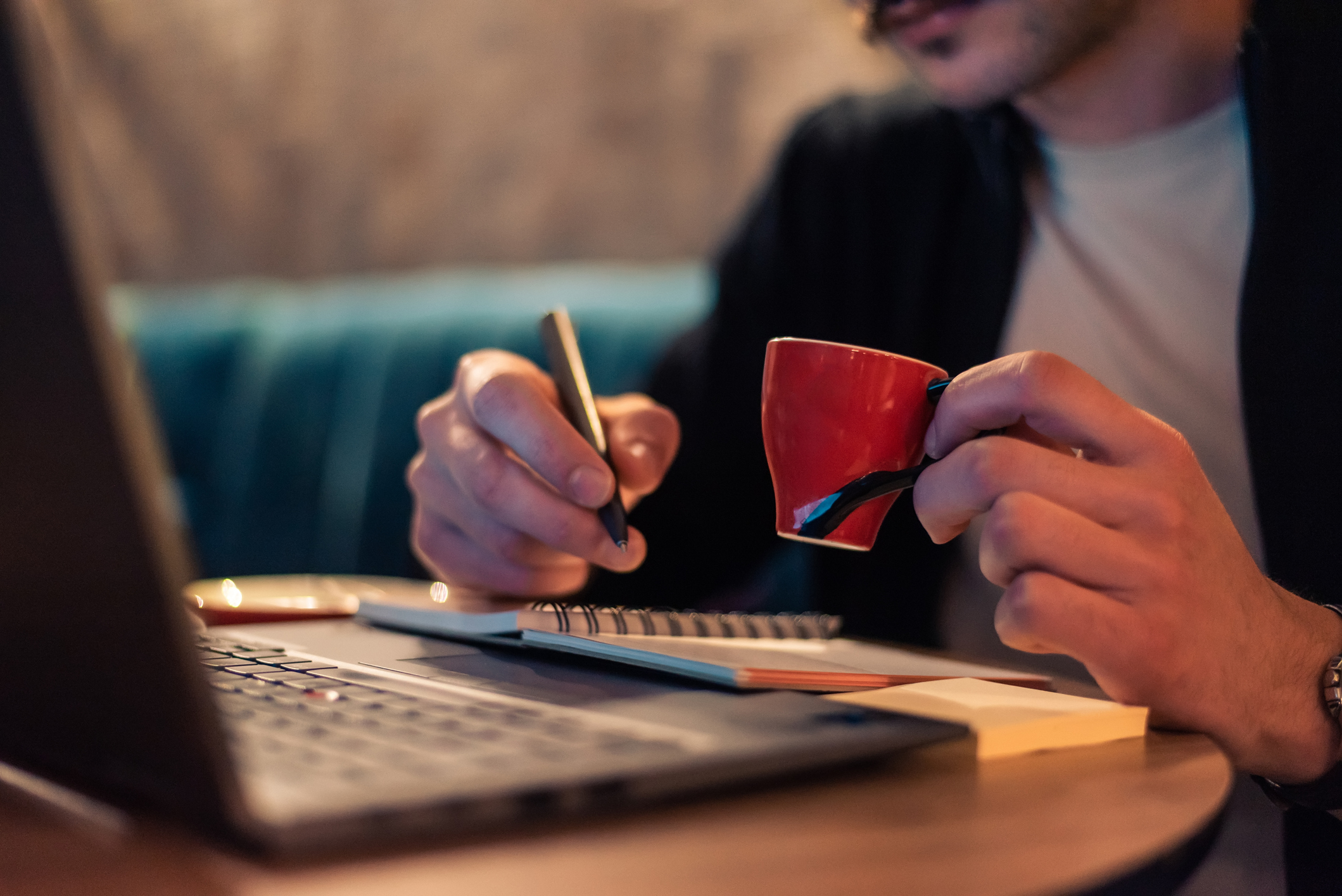 Un treballador escriu a la seva agenda mentre es pren un cafè