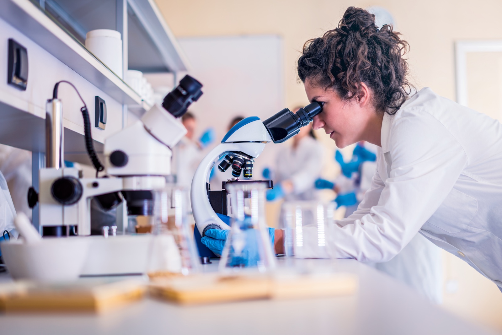 Una tècnica observa una mostra a través d'un microscopi