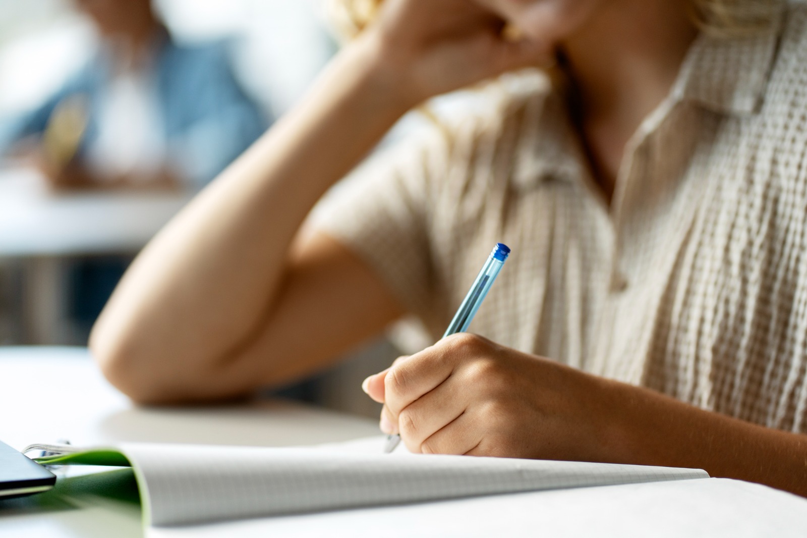 Un alumne en una aula escriu en un quadern. 
