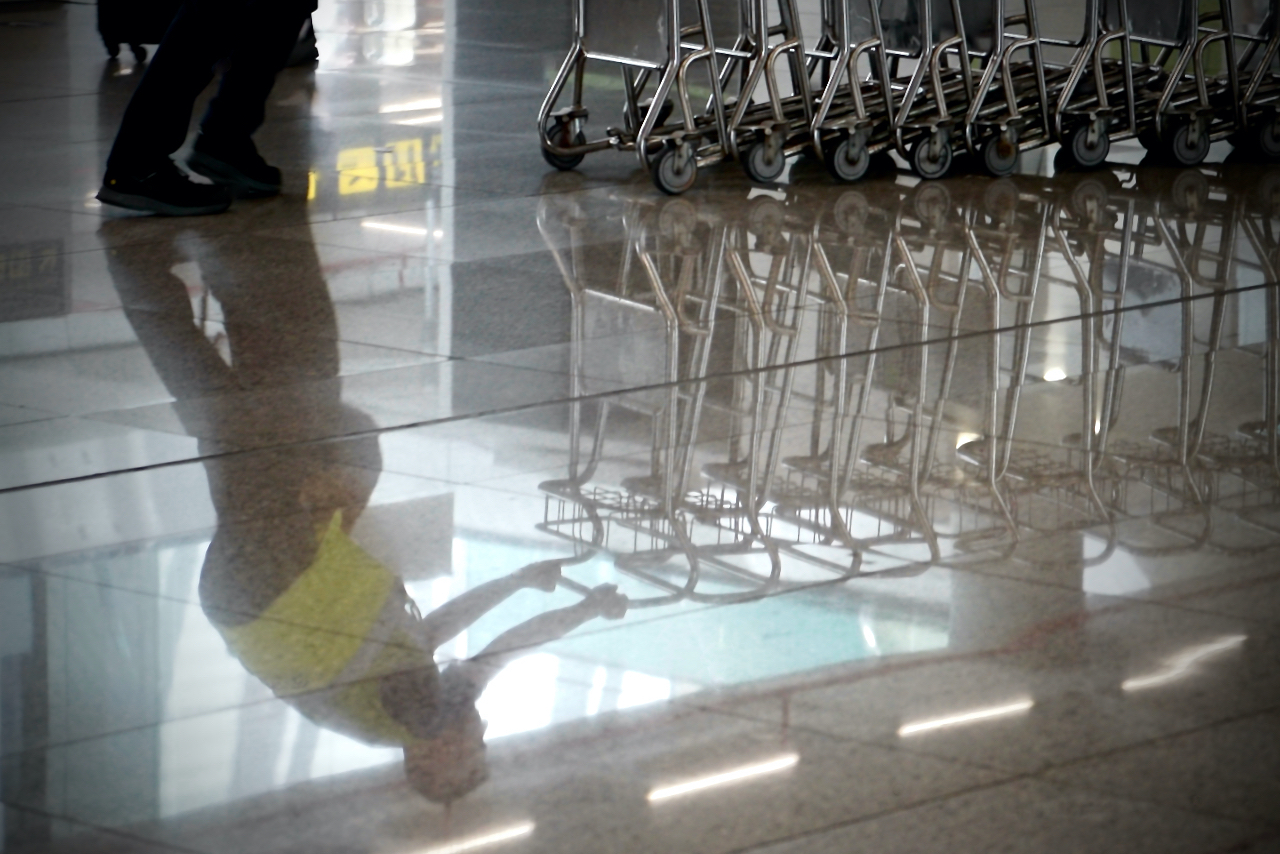 Reflex d'un treballador de l'aeroport empenyent uns carrets.
