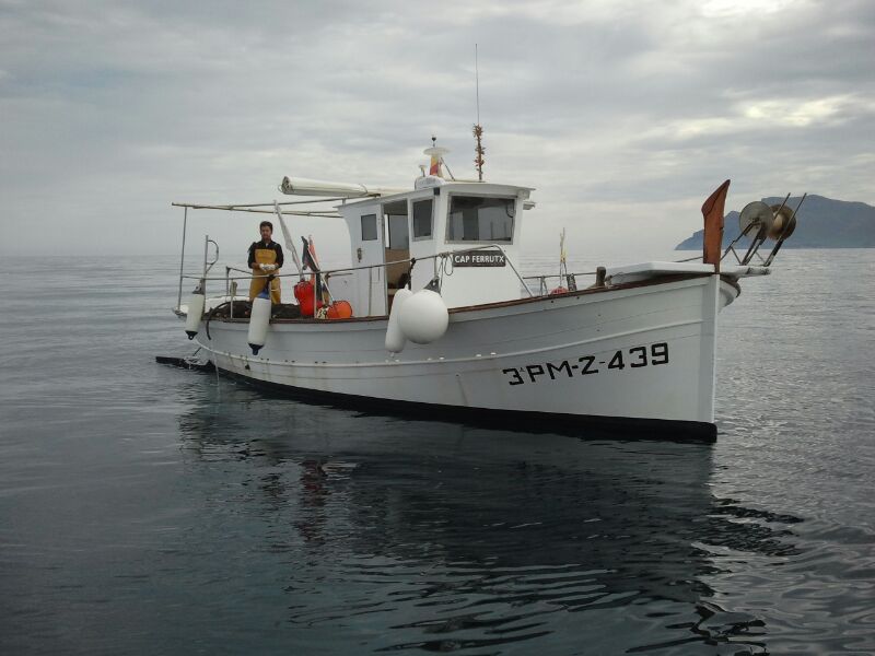 Embarcació de pesca enmig del mar amb un pescador.